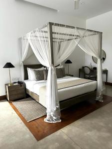 瓦都瓦The Villa by Contemporary Ceylon的卧室配有带白色窗帘的天蓬床