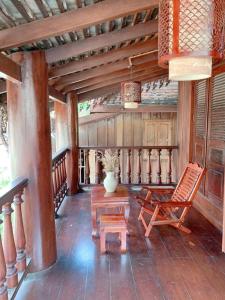 琅勃拉邦遗忘时光Guesthouse Sky dragon Guesthouse的门廊配有摇椅和桌子
