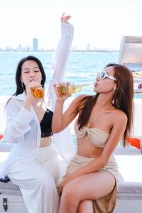 岘港Golden Rose Hotel by THG的两个女人坐在船上喝啤酒