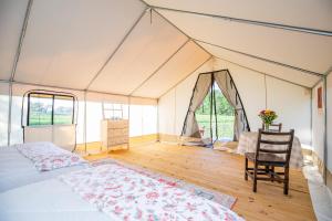 CassvilleRoaring River Luxury Glamping #5的帐篷内的卧室,配有一张床和椅子