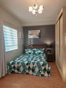 宿务Mivesa Garden Residences的一间卧室配有一张带绿色和白色棉被的床