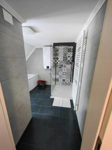 波斯托伊纳Sana的带淋浴的浴室和黑色瓷砖地板。