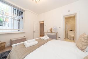 伦敦Kensington luxury flat with patio的白色的卧室设有一张大床和一个窗户