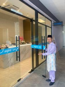 普崇The Signature Serviced Suites Puchong的一个人站在商店前