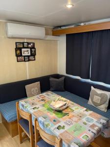 萨尔拉拉卡内达Charmant Mobil-home climatisé avec 2 chambres et entièrement équipé, sauf draps en option, pour 5 personnes au maximum的客房设有桌子、带桌椅的沙发、