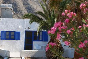佩里萨阿波罗客房旅馆的蓝白色的建筑,有棕榈树和粉红色的花朵