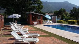 圣代佩德罗Hotel - Pousada 3 Marias的一组草坪椅和一个无边游泳池