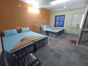 普里BRUNDABATI YATRI NIWAS的一间设有两张床和椅子的房间