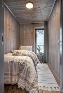 斯特兰达Premium Penthouse near Strandafjellet Ski Resort & Geiranger - Panoramic Mountain Views & Sauna的一间卧室设有木墙和一张带窗户的床