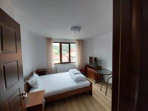 科普里夫什迪察Kъща за гости Демария的一间卧室配有一张床、一张桌子和一个窗户。