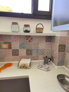 斯佩基亚Casa Salento的厨房柜台设有水槽,墙上铺有瓷砖。