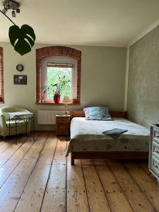 宇格维斯Przytulne Siedlisko的一间卧室配有一张铺有木地板的床和窗户。