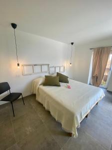 马尔切西内Relais PINF的白色卧室配有一张大床和椅子