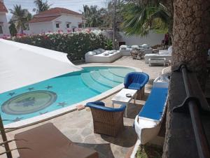 瓦塔穆Boutique Hotel Nyumbani Tembo的一个带蓝色椅子和桌子的游泳池