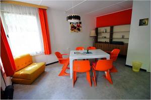 德兰斯克DDR Bungalow direkt am Strand auf Rügen的一间配备有白色桌子和橙色椅子的用餐室