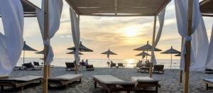 都拉斯Villa Eden 111, Perla Resort, Bay of Lalzi的沙滩上,有遮阳伞,有人坐在沙滩上