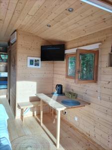 MargonLa roulotte de Jane的小木屋配有桌子和墙上的电视