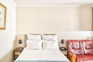 开普敦Goodwood Oasis Free WiFi-Parking 2的一间卧室配有一张床和一张皮椅