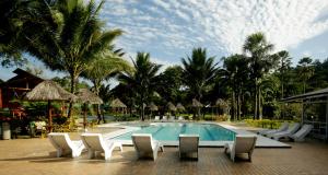 米萨华丽港Misahualli Amazon Lodge的一个带桌椅的游泳池,棕榈树