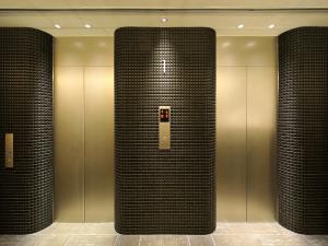 福冈博多绿色附楼饭店的大堂设有两部带黑色瓷砖柱的电梯