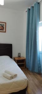 塔维拉瓜斯旅馆的一间卧室配有床和蓝色窗帘的窗户