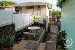 檀香山Hostel Honolulu的一个带桌子和长凳的小后院