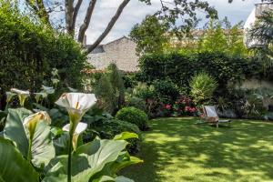 拉罗谢尔Escale Rochelaise B&B, SPA bain nordique et sauna tonneau的花园,花园内有白色的花朵和椅子