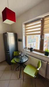 华沙Warszawa Bemowo Pokoje的厨房配有桌子、绿色椅子和冰箱