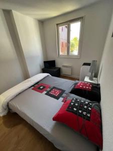 勒泰克Le Nid du Teich的一间卧室配有红色和黑色枕头的床