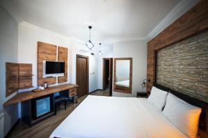 格克切达镇İmroz Adali's Butik Otel的一间卧室配有一张床和一张书桌及电视