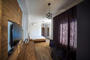 格克切达镇İmroz Adali's Butik Otel的一间配有电视的客厅和一张位于房间内的床