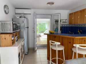 滨海萨纳里Bel Appartement avec Jardin pour 4 Personnes Climatisé avec Accès plage de la Gorguette à pied的厨房配有冰箱和带凳子的台面