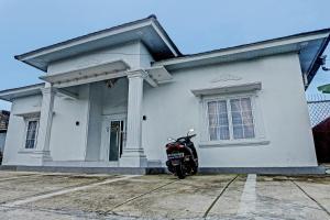 邦加槟港OYO 92708 Hotel Mufasa Syariah的停在白色房子前面的摩托车