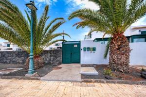 科斯塔特吉塞Casa Costa Esmeralda-shared pool的一座带绿门和两棵棕榈树的建筑