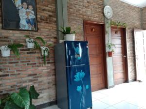 棉兰Bua Guest House的砖墙旁的蓝色冰箱,上面涂有鲜花