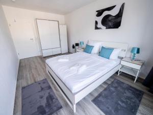 曼海姆City Suite - 5 Min to HBF的卧室配有带蓝色枕头的大型白色床