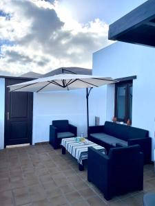 阿索马达Canto Rojo, La Asomada con vistas a Lobos的庭院配有两把椅子、一张桌子和一把遮阳伞