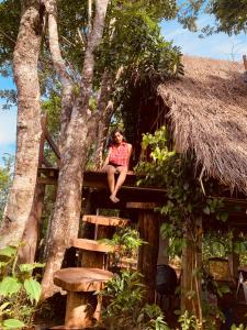 贝里胡罗亚Kale Cottage Belihuloya的坐在树屋顶上的女人