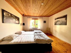 SkinnskattebergSjönära lantgård i Bergslagen的一间卧室设有一张带木制天花板的大床