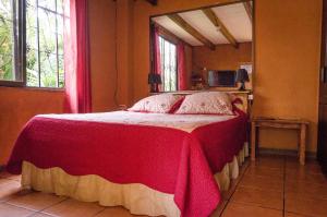 阿拉胡埃拉Hotel Chalets Los Volcanes的一间卧室配有一张带红白毯子的床