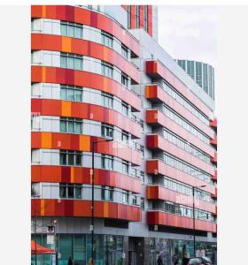 伦敦Tee SweetLux Apartment的一座高大的红色和橙色建筑,前面的人