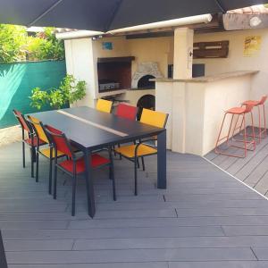 马里尼亚讷Joli haut de villa 3 chambres climatisé avec jacuzzi的露台上的桌椅和遮阳伞