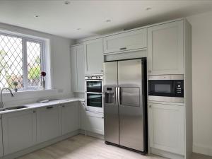滨海弗林顿Walton House的厨房配有白色橱柜和不锈钢冰箱