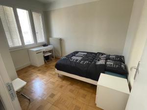 维勒班T4 3 Chambres proche grattes ciel, Villeurbanne, meublé的一间卧室配有一张床、一张书桌和两个窗户。