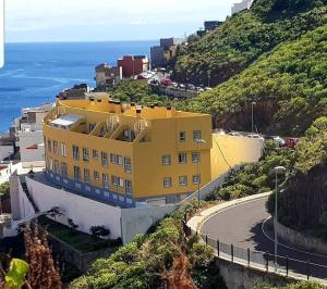 San AndrésLas Teresitas Apartment的海边小山上的黄色建筑