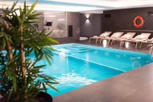 里斯本MASA Hotel & Spa Campo Grande Collection的游泳池,位于带椅子的房间和游泳池