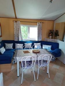 韦尔东的圣克鲁瓦Mobil home 6 personnes climatisation Sainte Croix du Verdon - Gorges du Verdon的客厅配有桌子和蓝色沙发