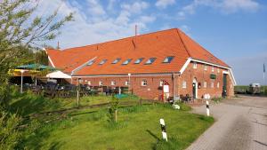 特希尔Hofcafé & Ferienhof Akkens的一座大型红砖建筑,带有橙色屋顶