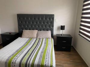 蒙特雷Luxury House in San Pedro Garza Garcia的一间卧室配有一张带黑色床头板和2个床头柜的床。