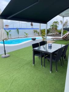 圣克鲁斯-德特内里费Tagoro Sunset View & Heated Pool Tenerife的一张桌子和椅子,放在泳池旁的黑伞下